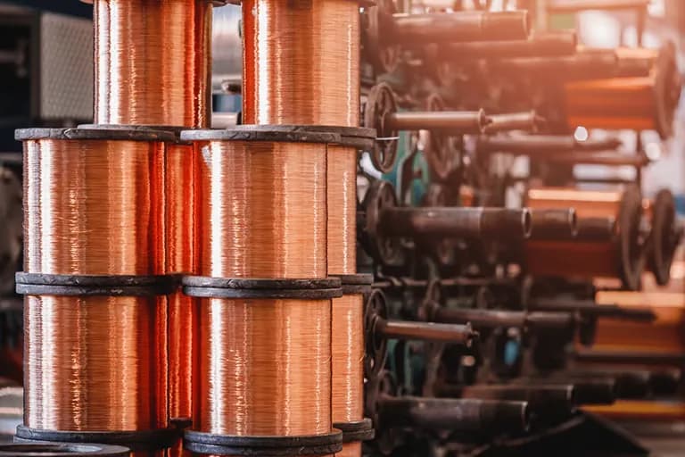 Spools of bright copper wire on a cable manufacturing line